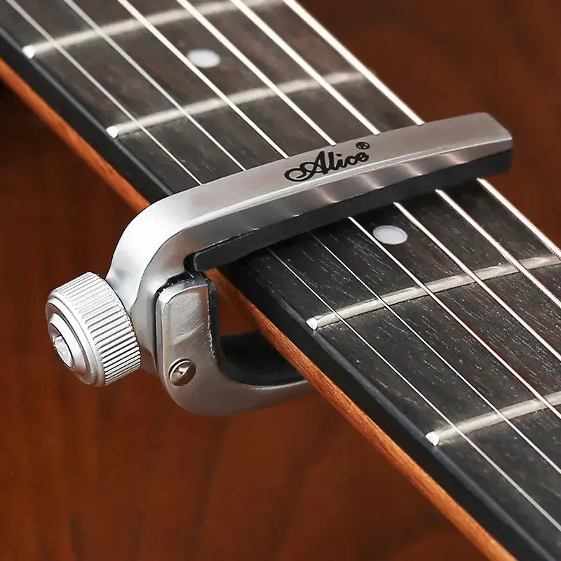 Guitar capo on an acoustic guitar with 'Alice' branding