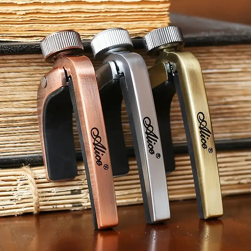 Three Alice brand guitar capos in different colors on a woven surface.