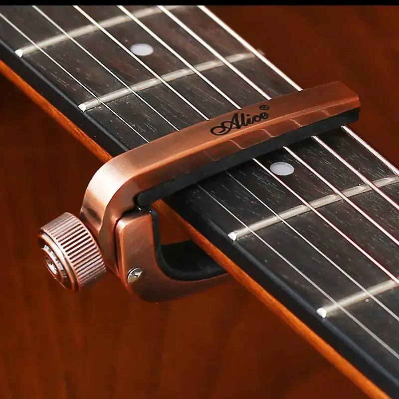 Guitar capo on a guitar with 'Alice' branding
