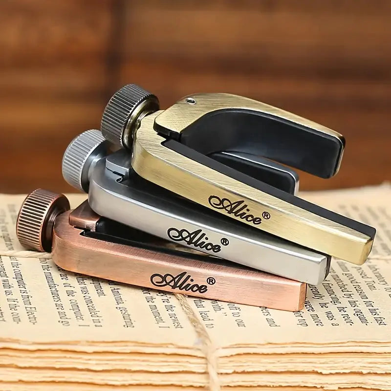 Three guitar capos in gold, silver, and bronze on a piece of paper with 'Alice' branding.