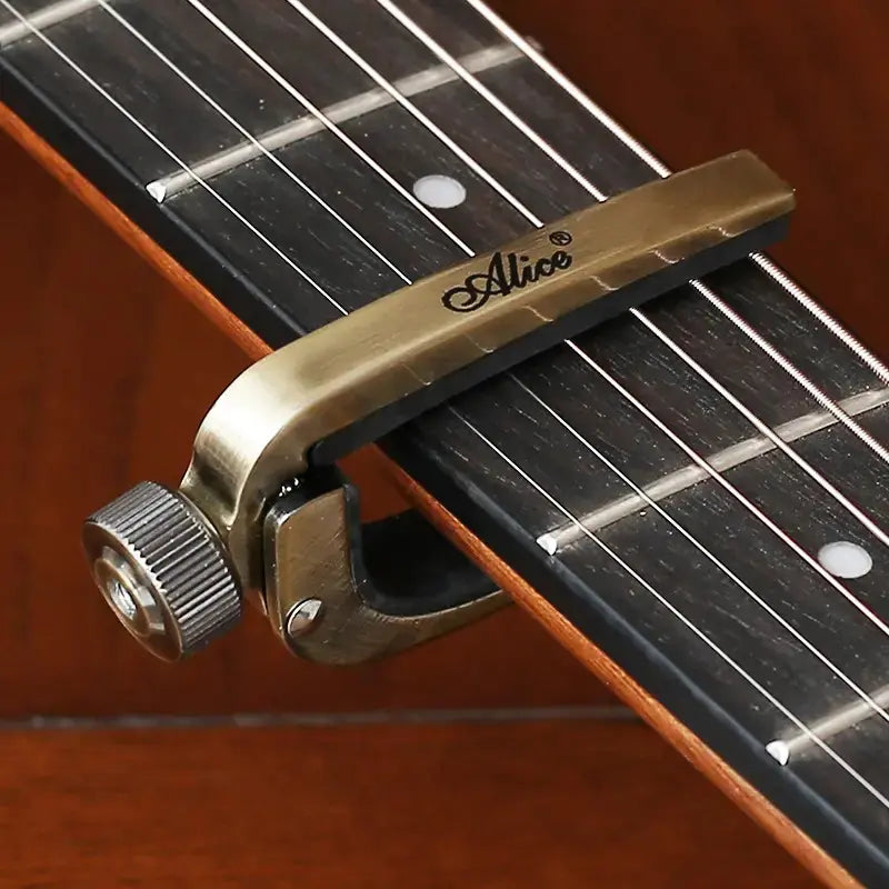 Guitar capo on an acoustic guitar with 'Alice' branding