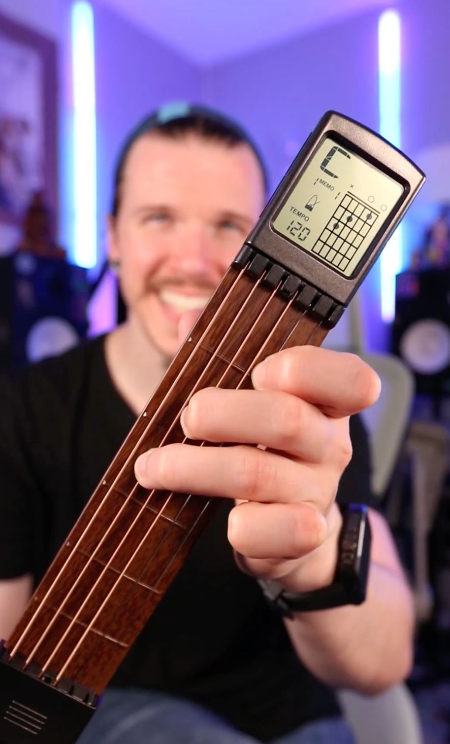 Person holding a digital guitar chord trainer with a blurred background